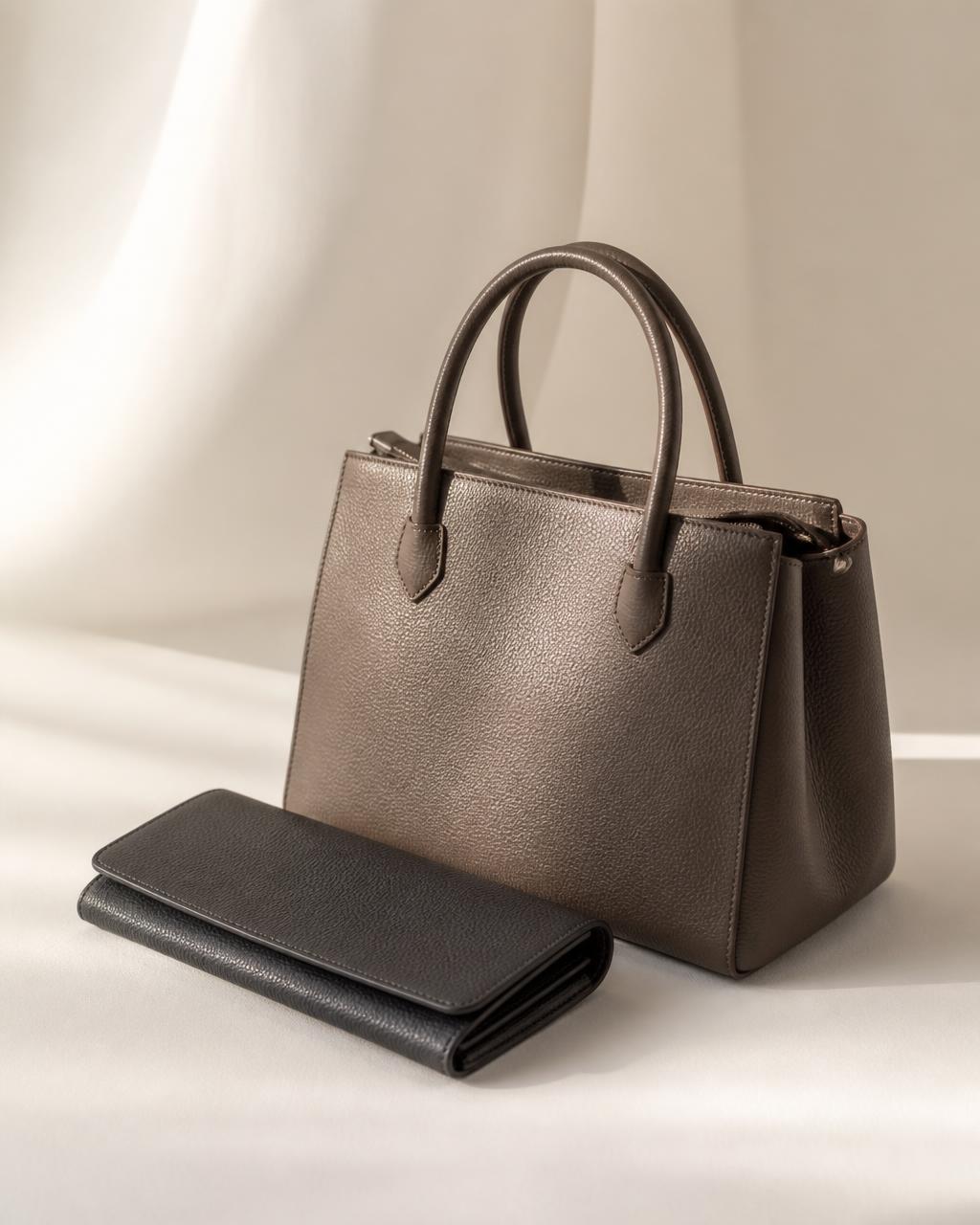Structured taupe leather handbag beside a dark leather wallet